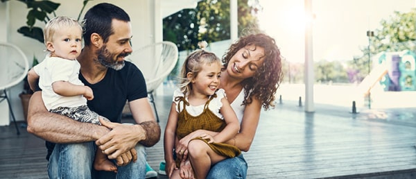 Family smiling in front of their new house, made possible by a mortgage using home buying guide.